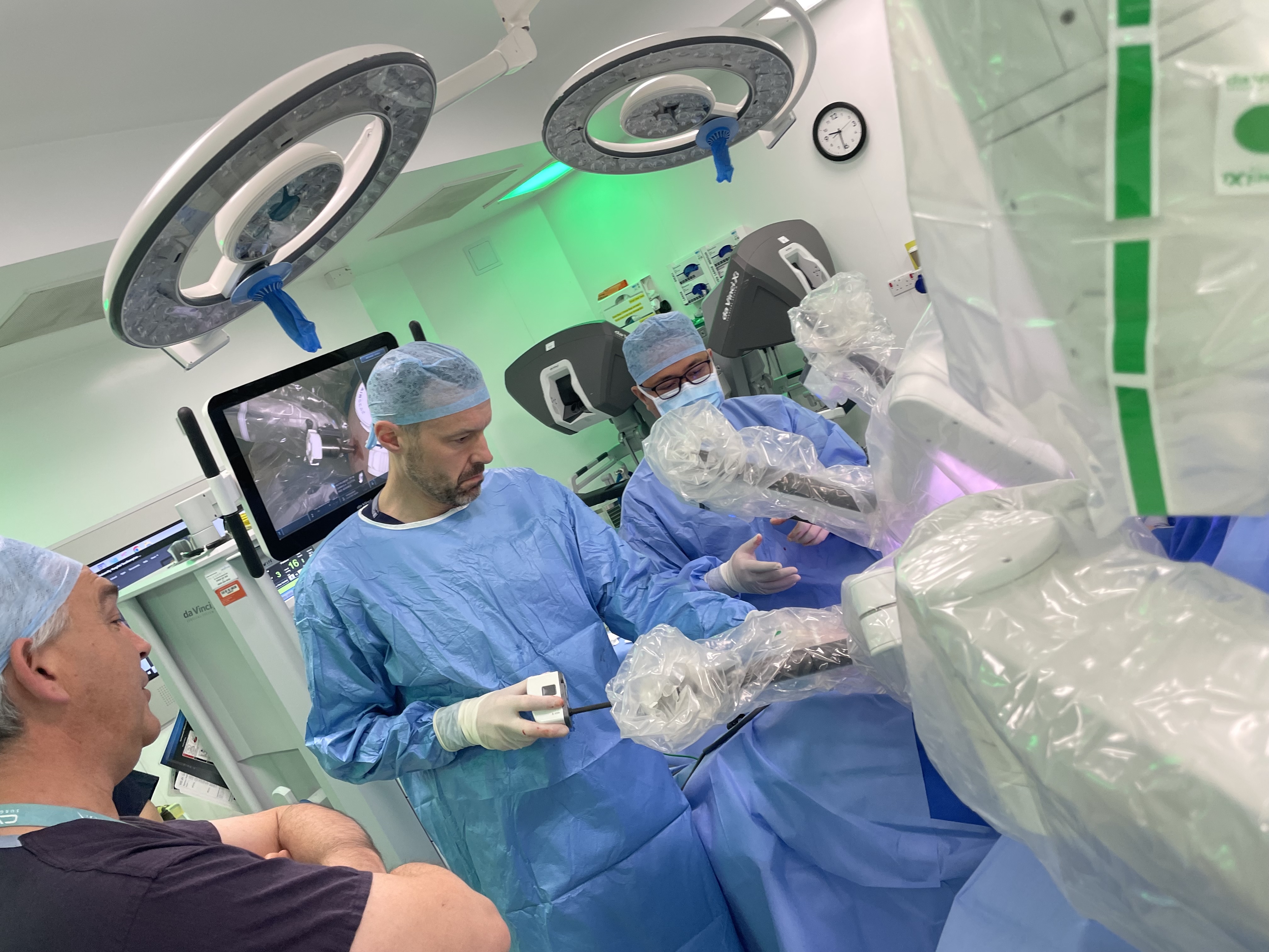 Three people working in an operating theatre, wearing scrubs