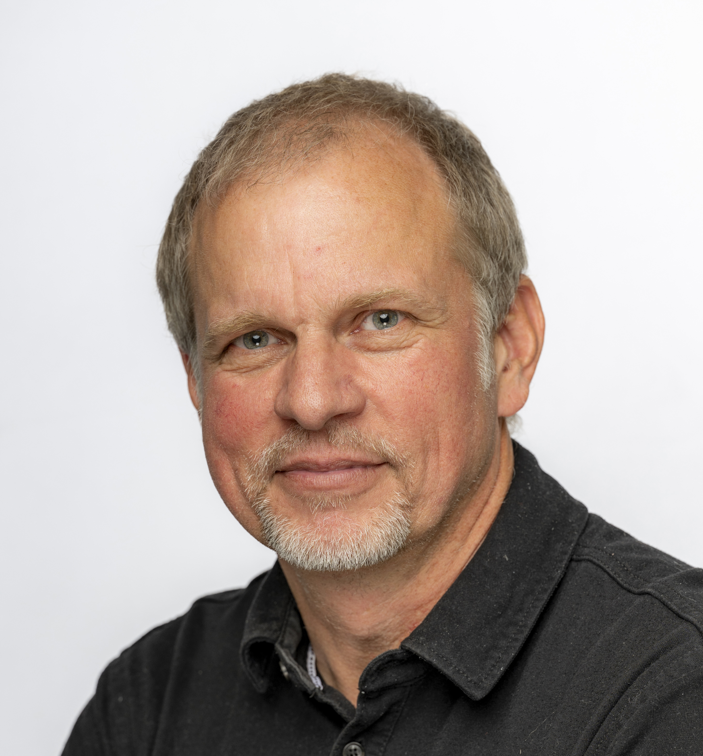 Head and shoulders view of a man looking to camera and wearing a black shirt.