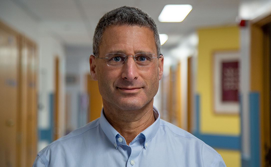 Head and shoulders view of a man wearing glasses and a light blue shirt.