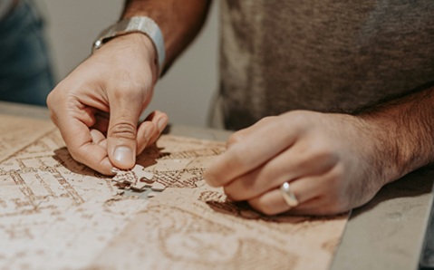 Close up of a man’s hands doing a puzzle 