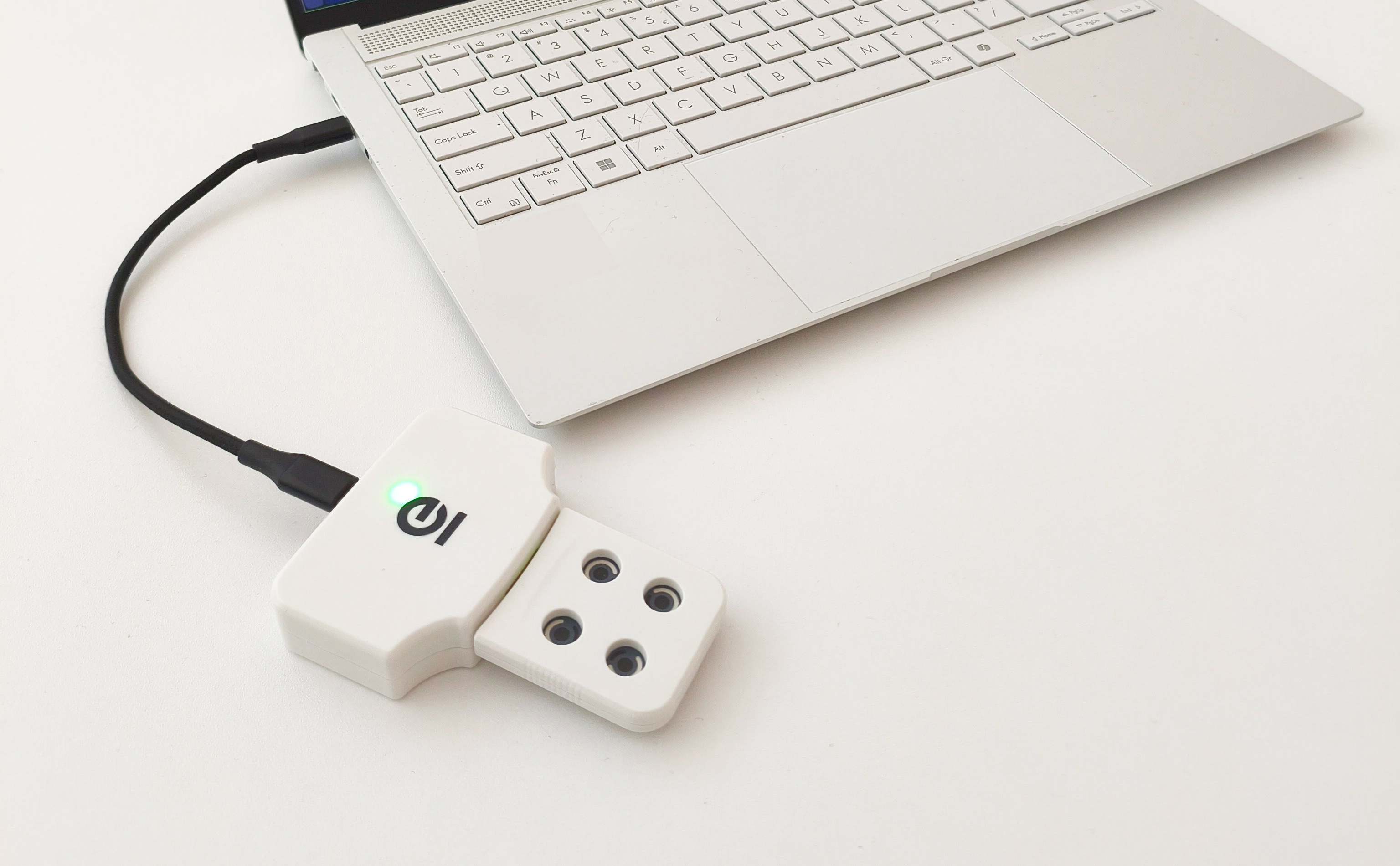 A laptop keyboard with a with a white rectangular infection testing device plugged into it.