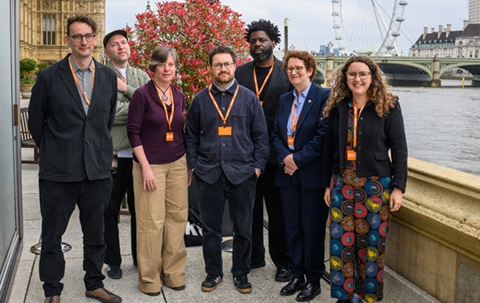 Group of 7 people standing outside, with the River Thames to the right and the London Eye in the distance.
