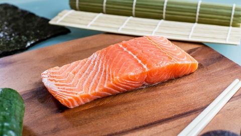 Close up image of a raw salmon steak on a wooden chopping board 