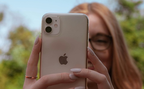 Close up of a woman taking a photo on her mobile phone. Half of the woman's face is obscured by her phone