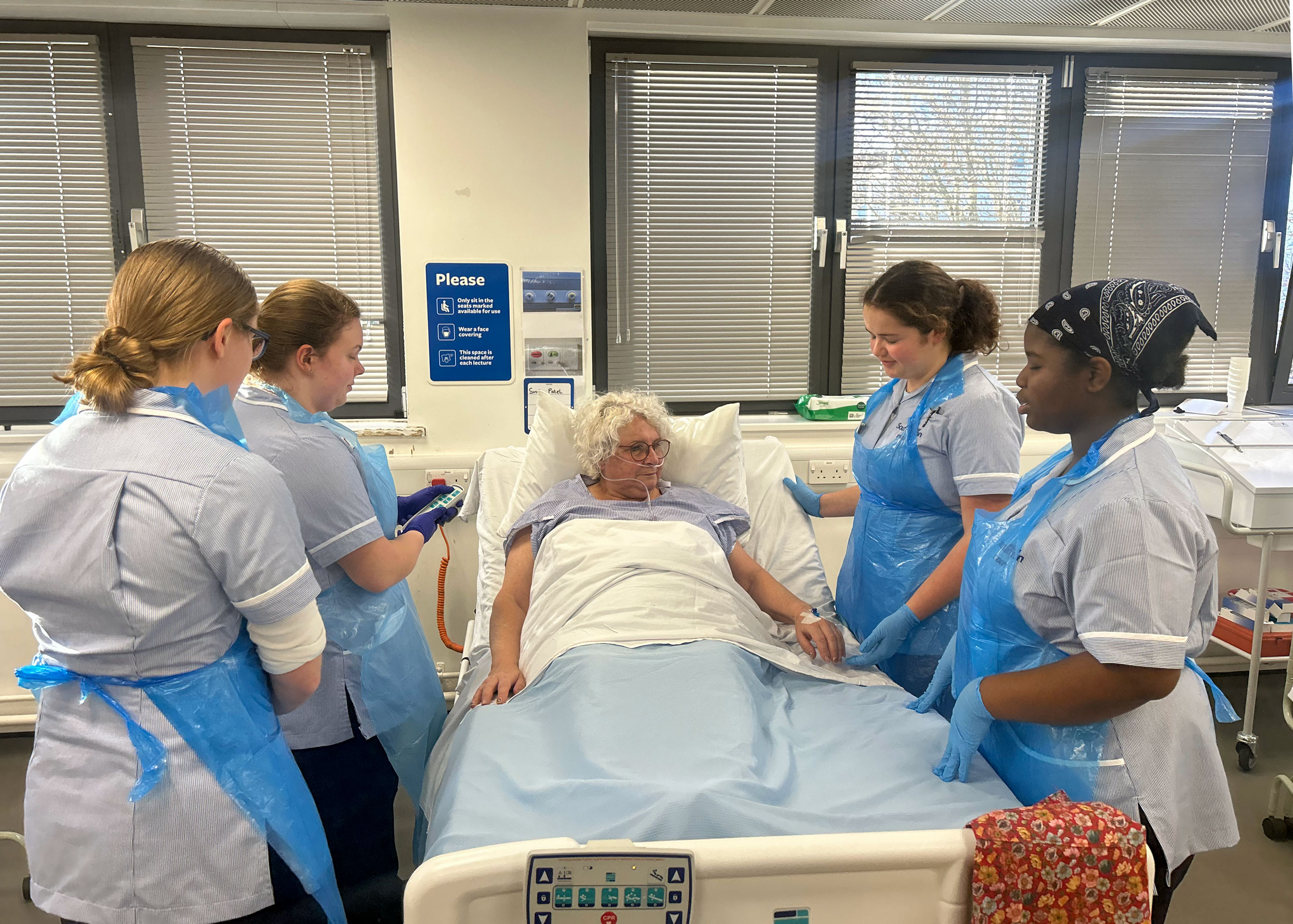 Four students stood around a bed with a patient in it 