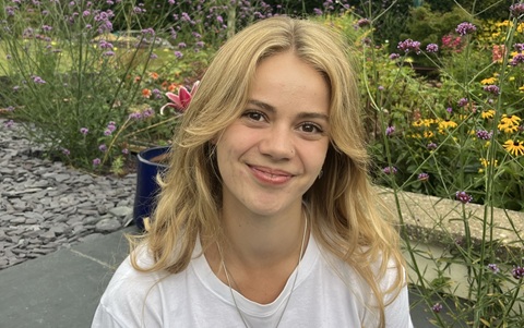 Head and shoulders photo of a young woman with long blonde hair wearing a white top