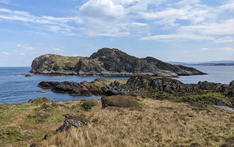 Coastal view of the Garvellach Islands with rocky cliffs and grassy foreground.