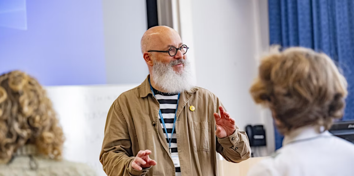 A man stands in front of a classroom and speaks
