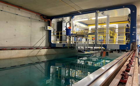 A large tank of water with a steel platform suspended above it, housed inside a concrete chamber