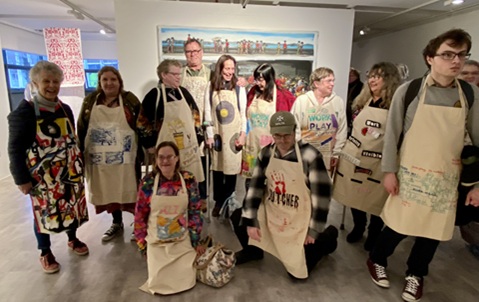 A group of adults standing wearing aprons with artwork on them