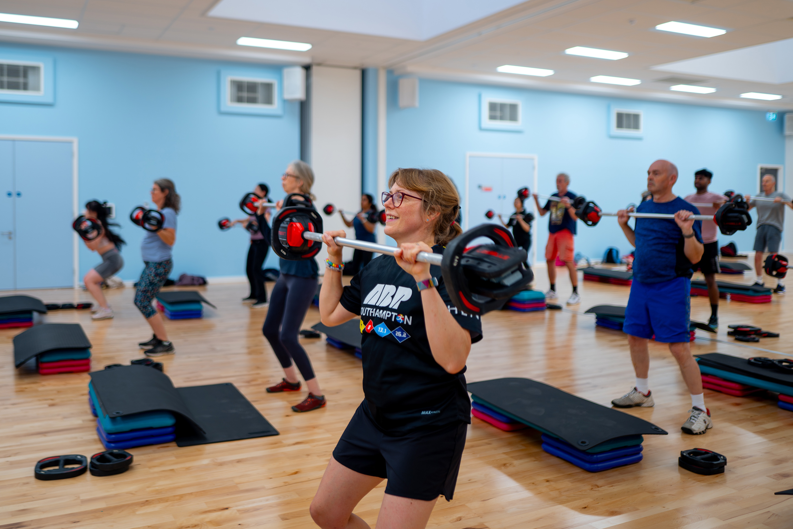 Gym-goers exercising with barbells