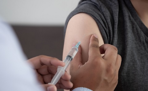 A close up of a person getting a vaccine injection into their upper arm