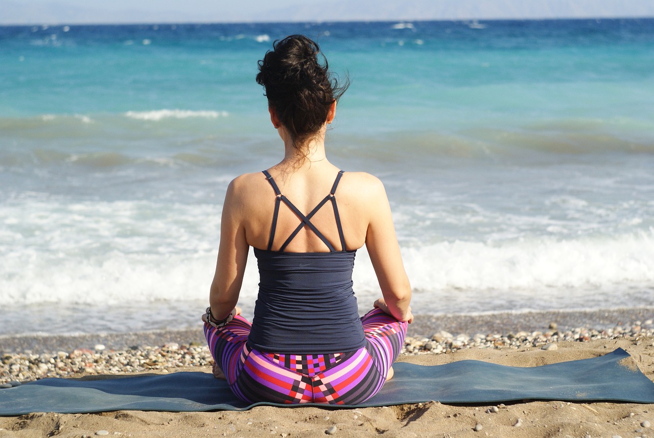 Woman on a beach sitting practicing mindfulness.