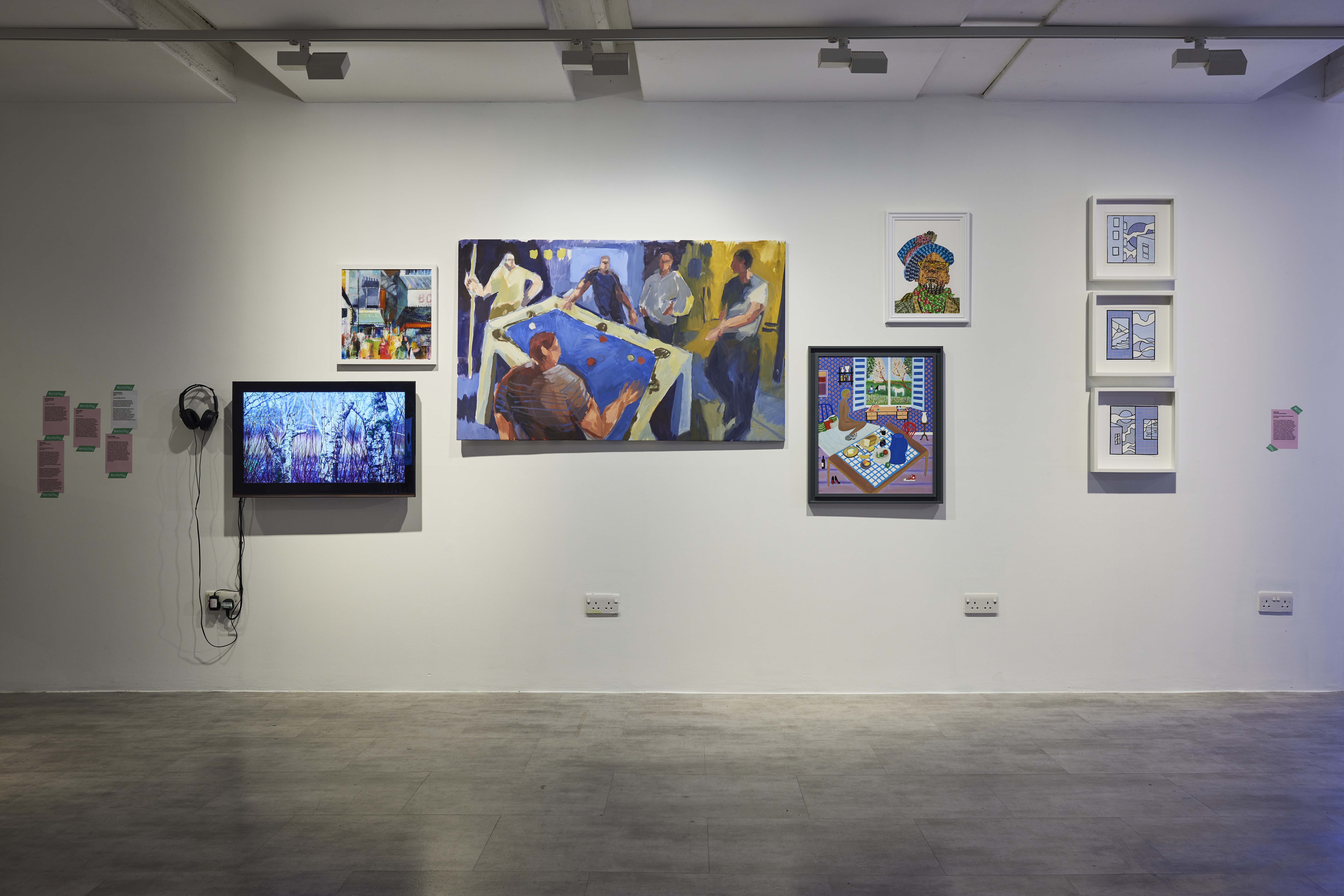 A gallery wall with several colourful artworks displayed, as well as a TV monitor showing artwork.