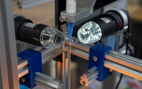 Close-up image of two torch-like lights pointing at a syringe with yarn coming out of it