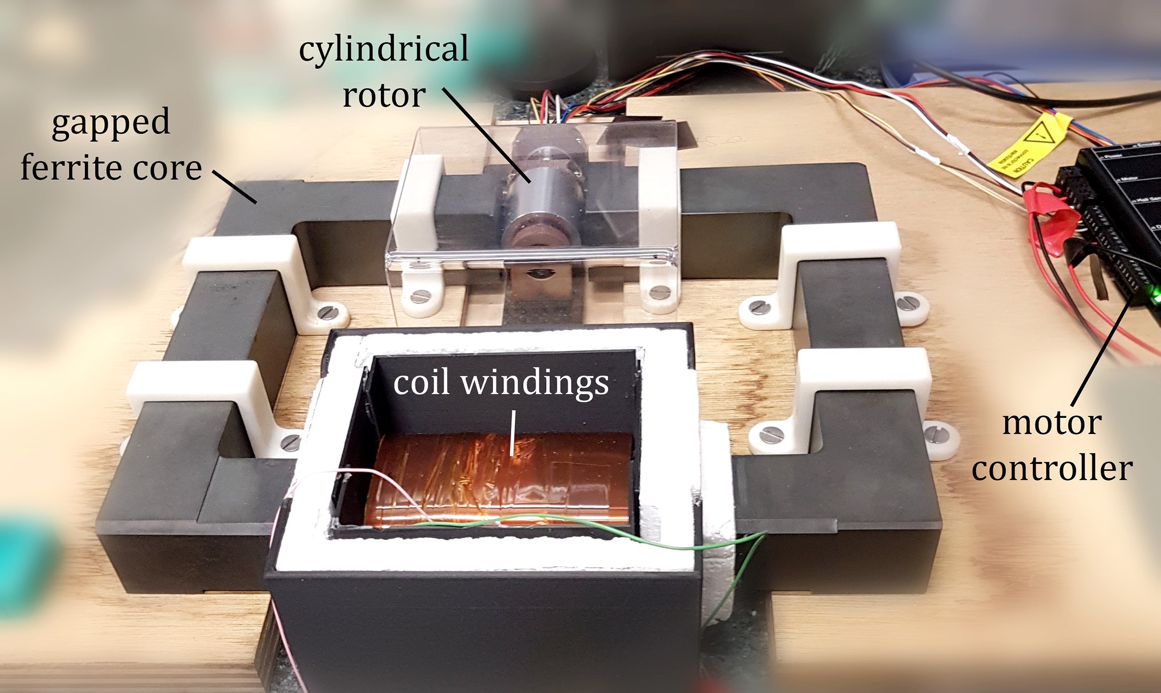 Small metal blocks arranged in a square on a wooden board with a cylinder at one end attached to a motor.