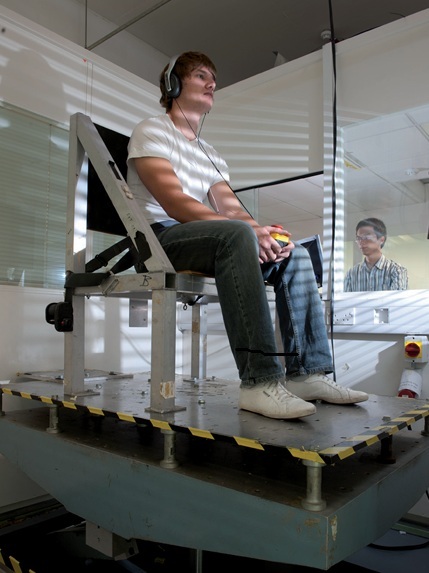 Participant seated on a vertical vibration platform used to study human response to whole-body vibration