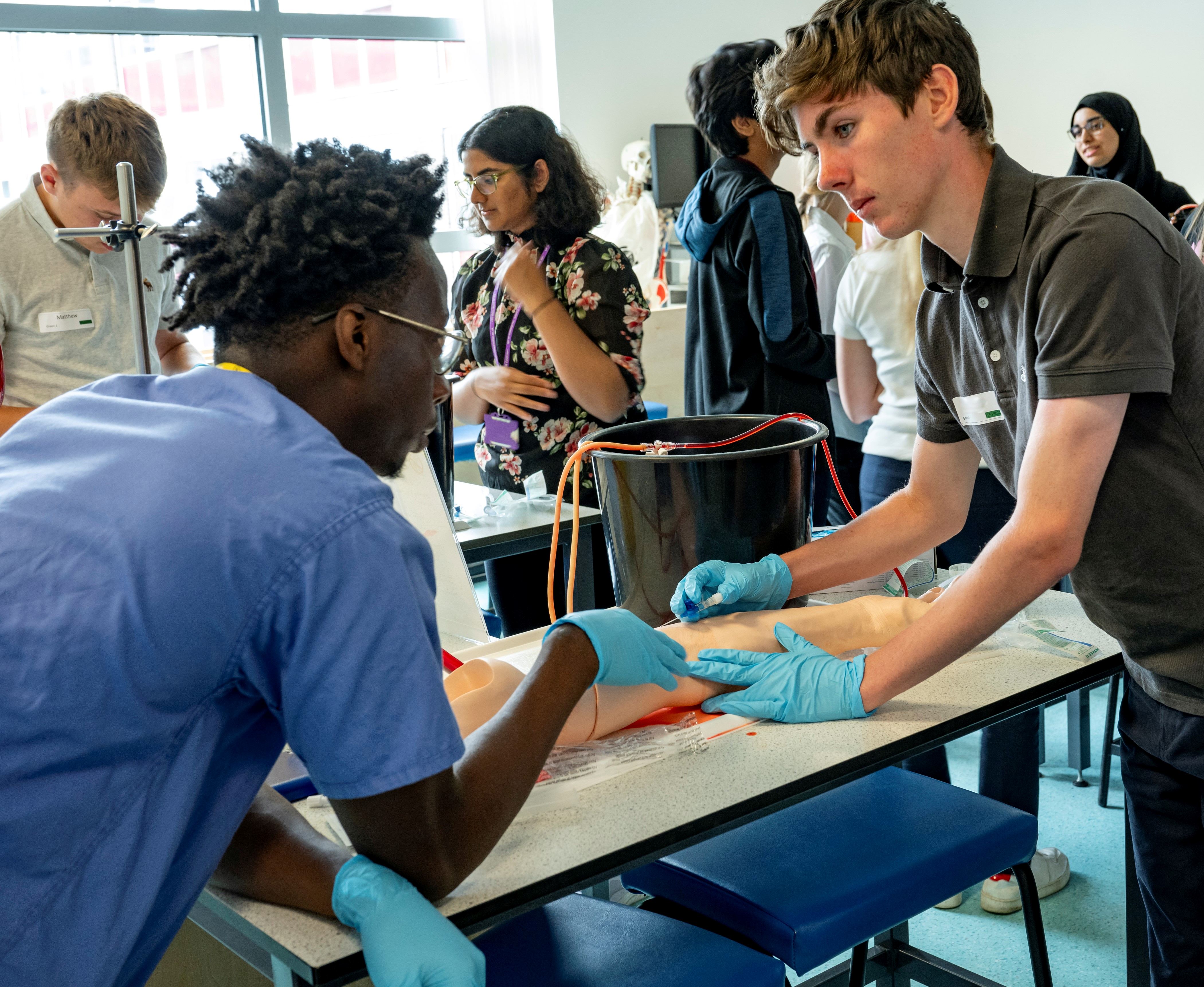 A small group of students taking part in a venesection practical session.