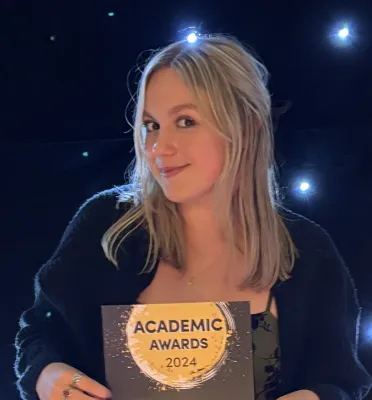Frankie Lochhead, BA Film and English student holding her Best Academic Impact certificate.