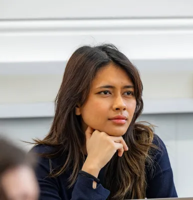 Head and shoulders portrait image of Gaby Lavenia, BA Philosophy and Politics student looking at the camera. She is resting her chin on her hand. 
