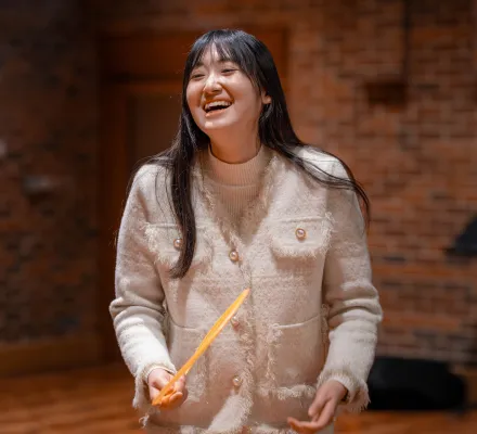 Ouwen Wang is laughing in a rehearsal in the Turner Sims hall.