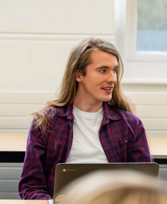 Head and shoulders portrait image of Ross Wilks, MA Philosophy student smiling and looking to the right. 