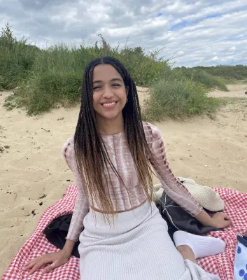 Laureen, BM4 student, sitting at the beach smiling at the camera.