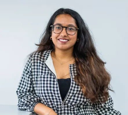 MSc Business Analytics and Management Science student, Chhavi is leaning on a table and smiling at the camera.