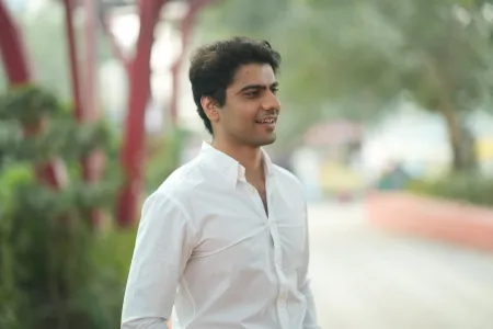 Law graduate and entrepreneur Rohit is standing looking to the right of the camera. There are out of focus trees and shrubs behind him.