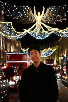 Jiachen is standing in front of christmas lights.