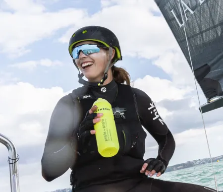 Hattie smiles happily, sailing in full gear in gentle waves