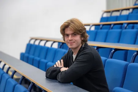 MSc Finance and Econometrics graduate, Stefan, sat in an empty lecture classroom smiling for a photo.