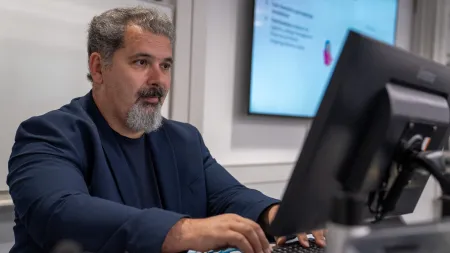 Professor Dimitrios Angelakis working on a computer, looking at a screen.