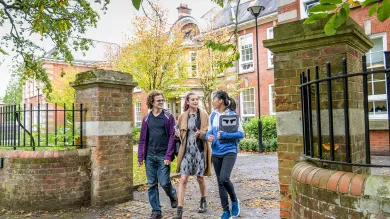 Students walking through gates outside the impressive buildings of Avenue Campus.