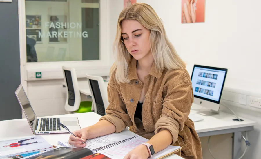 Female fashion marketing student sitting in the studio working on a magazine