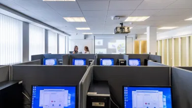 A view of workspaces in the social sciences experimental lab, with two students talking in the background