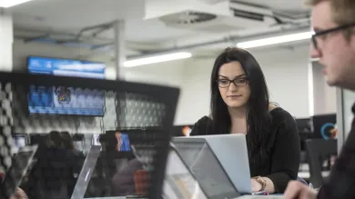 Two students with laptops sharing a table to work on a project together.