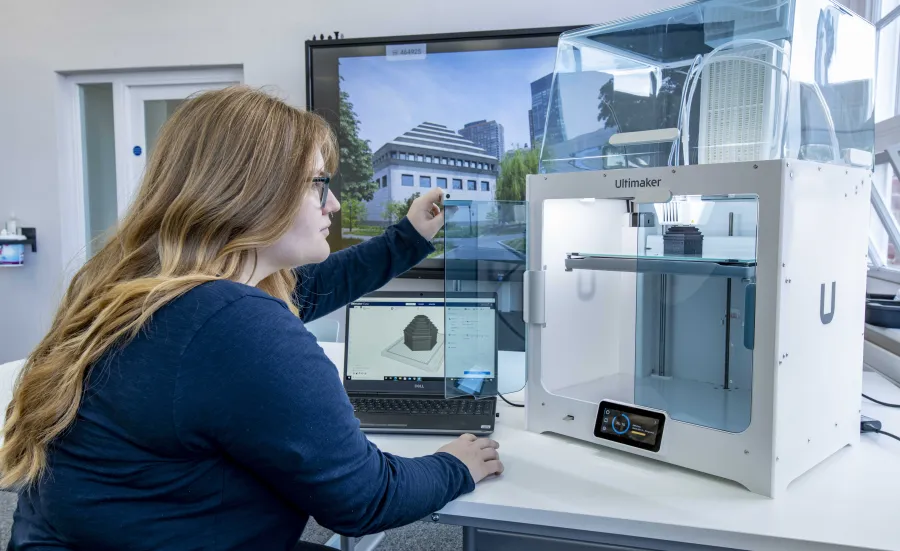 A student inspecting the finished construction of her latest 3D printed object.