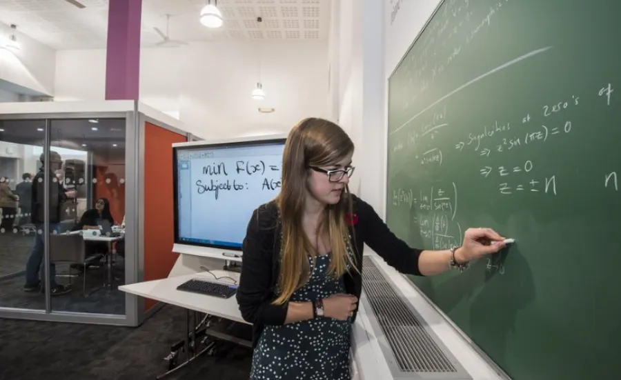 A student works on a maths problem using a blackboard in the maths student centre.