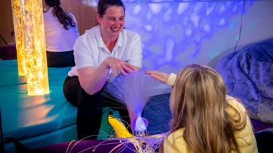 A healthcare students works with their young client in the multisensory room