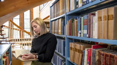 A student browsing by a bookshelf in Hartley Library