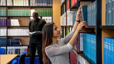 A student looking through bookshelves in the law library collection