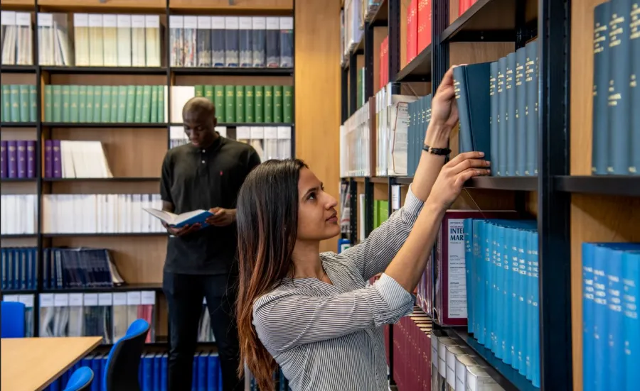 A student looking through bookshelves in the law library collection
