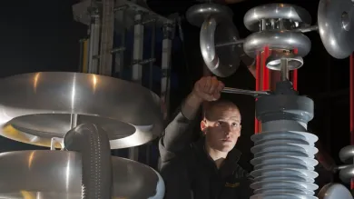 A student using a spanner to adjust a large piece of equipment in the high voltage lab.
