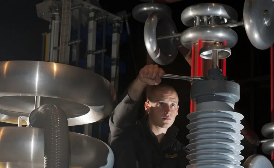 A student using a spanner to adjust a large piece of equipment in the high voltage lab.