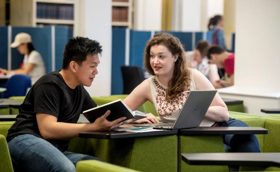 Two students collaborate on project work in a quiet learning space