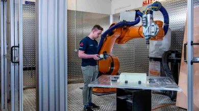 A student uses the robot arm in the engineering design and manufacturing centre