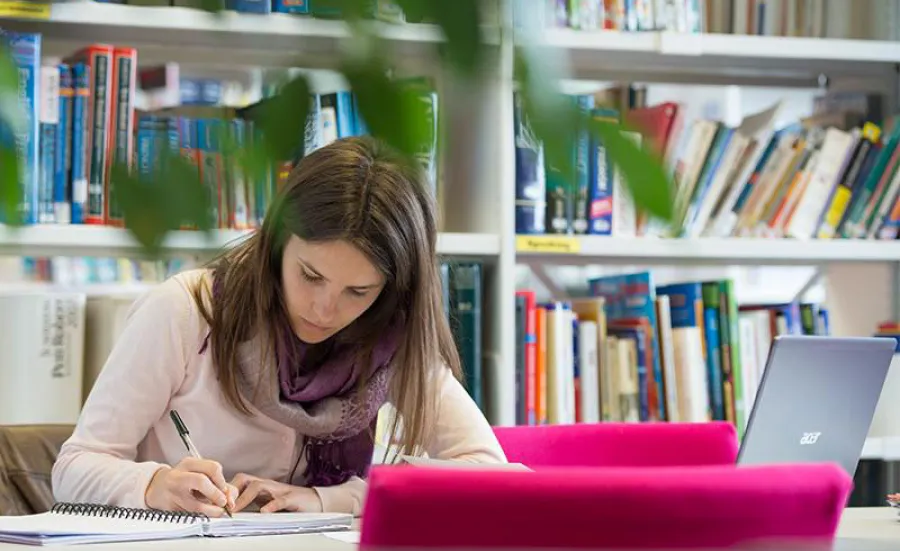 Student writing at desk