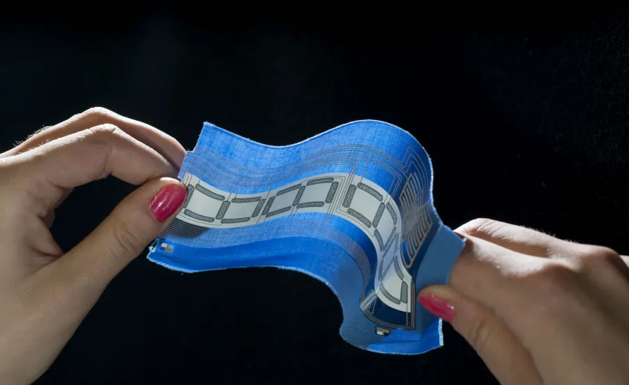 Two hands holding a piece of fabric with embedded circuitry