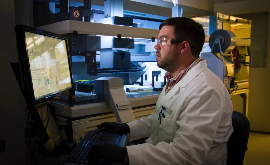 A man in lab sitting in fromt of a computer.